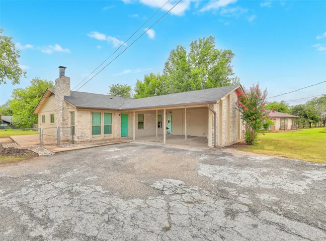 A stone and brick exterior welcomes, offering a covered carport and a spacious front yard.