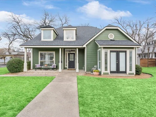 A charming green residence presents an inviting front porch and a well-kept lawn, offering delightful curb appeal.