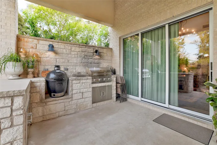An outdoor kitchen features built-in stone details and wide sliding glass doors.