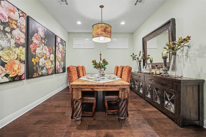 Rich hardwood flooring complements the elegant recessed lighting in this welcoming dining space.