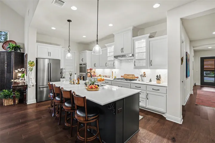 Gleaming stone countertops and rich hardwood floors define this open chef's kitchen.