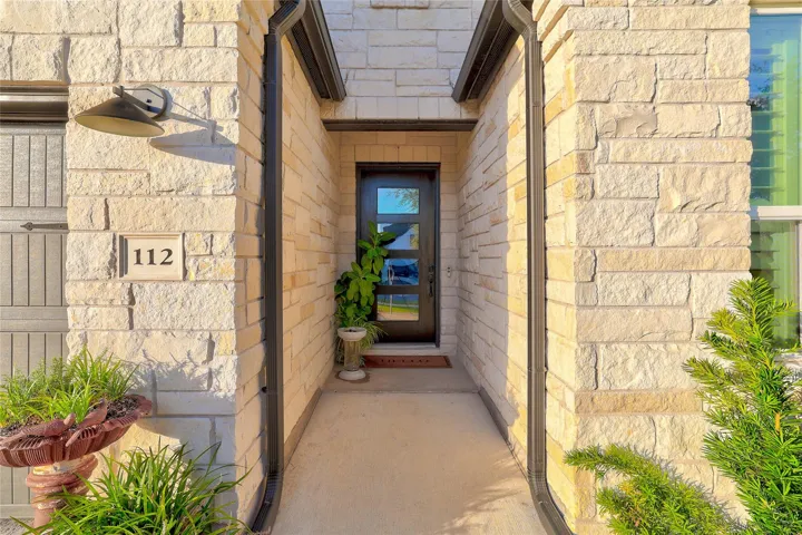 An inviting stone-clad alcove frames the contemporary front entry.