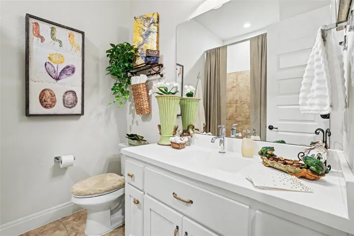 A spacious vanity mirror reflects the tiled walk-in shower area.