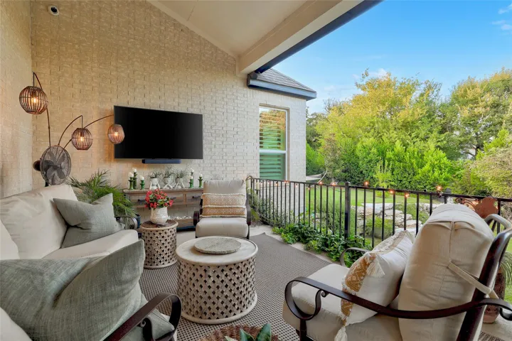 An inviting covered patio features a brick wall, neutral flooring, and views of lush greenery.