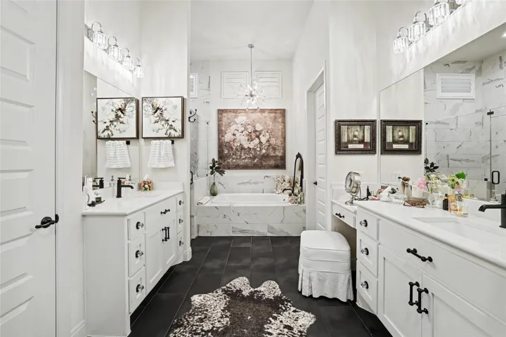 A spacious layout showcases a soaking tub set against marble wall detailing and dark tile flooring.