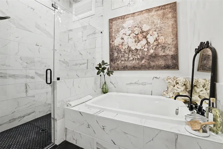 Elegant marble-patterned tile surrounds a deep soaking tub and adjacent walk-in glass shower.