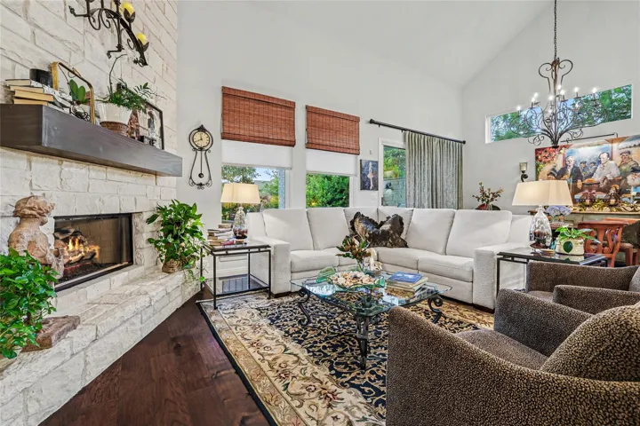 Rich hardwood flooring complements a floor-to-ceiling stone fireplace in this vaulted living space.