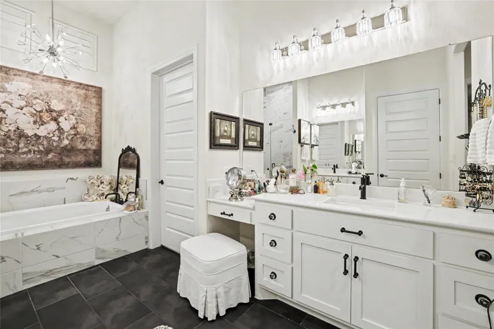High ceilings and stone finishes elevate this refined bath space featuring a soaking tub.