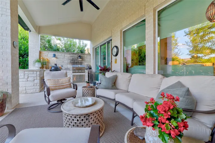 An inviting covered patio offers brick accents, concrete flooring, and a stone outdoor kitchen setup.