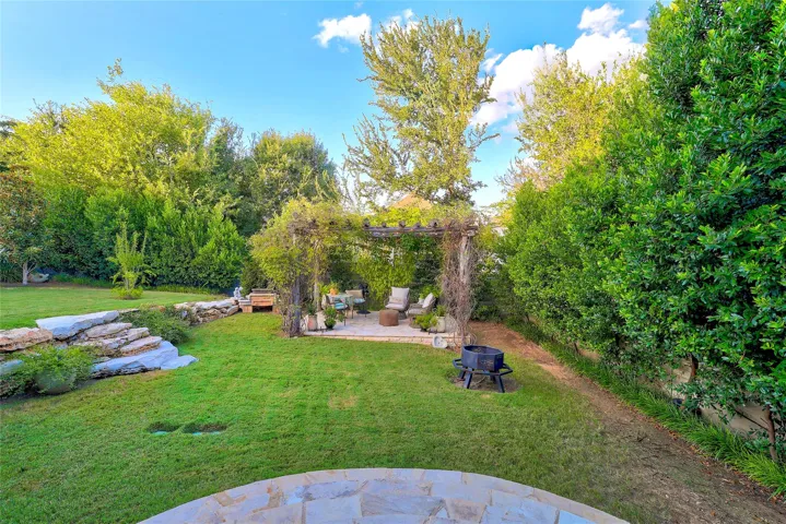 Mature trees and lush perimeter hedging frame a private lawn with integrated stone terrace details.