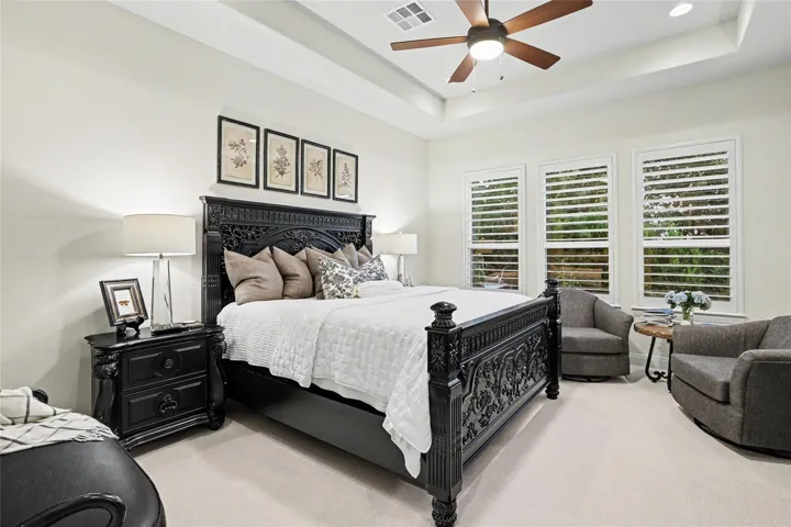 High tray ceilings and classic wood shutters elevate this peaceful bedroom retreat.
