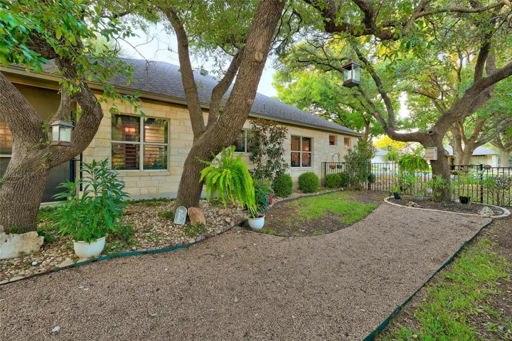 Side yard at twilight with crushed granite pathway, soaring trees, and wrought iron fence back yard with gate.  Mulched flowerbeds & some grassy areas for your pups...Low maintenance...