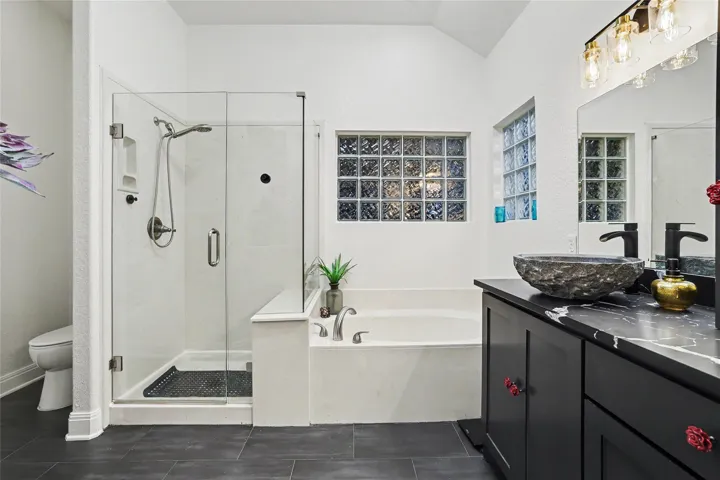 A semi-private commode area is tucked away beside the walk in shower.  The glass shower wall & door were updated.  The glass block window has the screened in patio on the other side...
