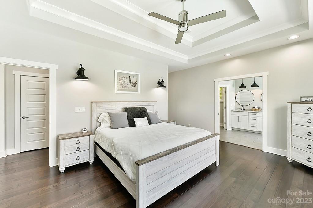 Primary Bedroom with Double Tray Ceiling, Wood Floors, Fan and Pocket Doors to Primary Bath