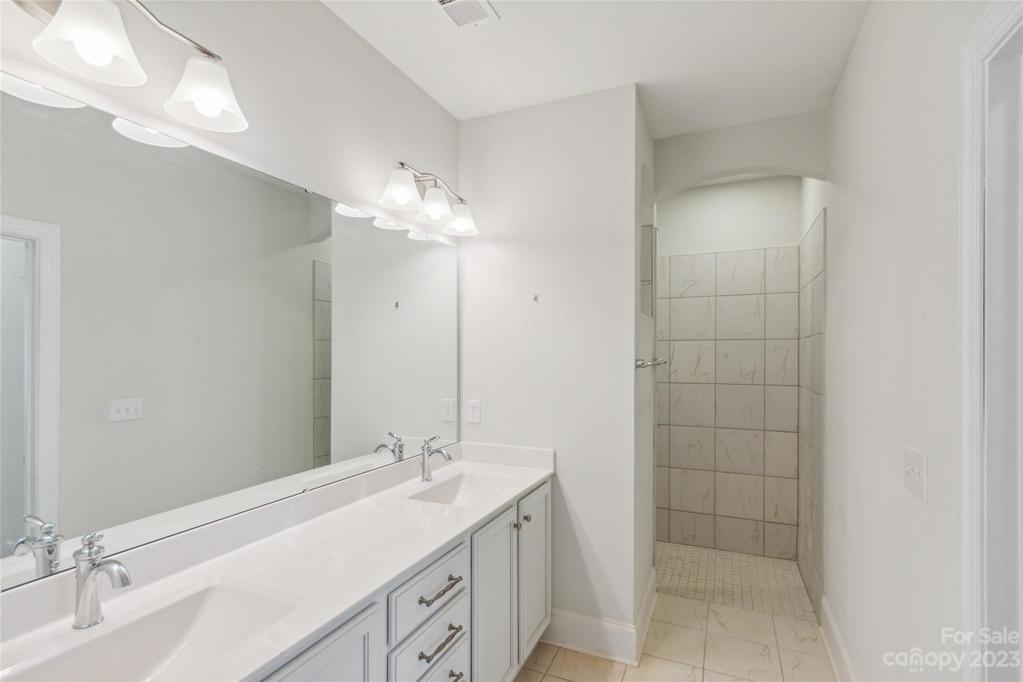 Crisp and clean primary master suite with zero threshold entry to shower.