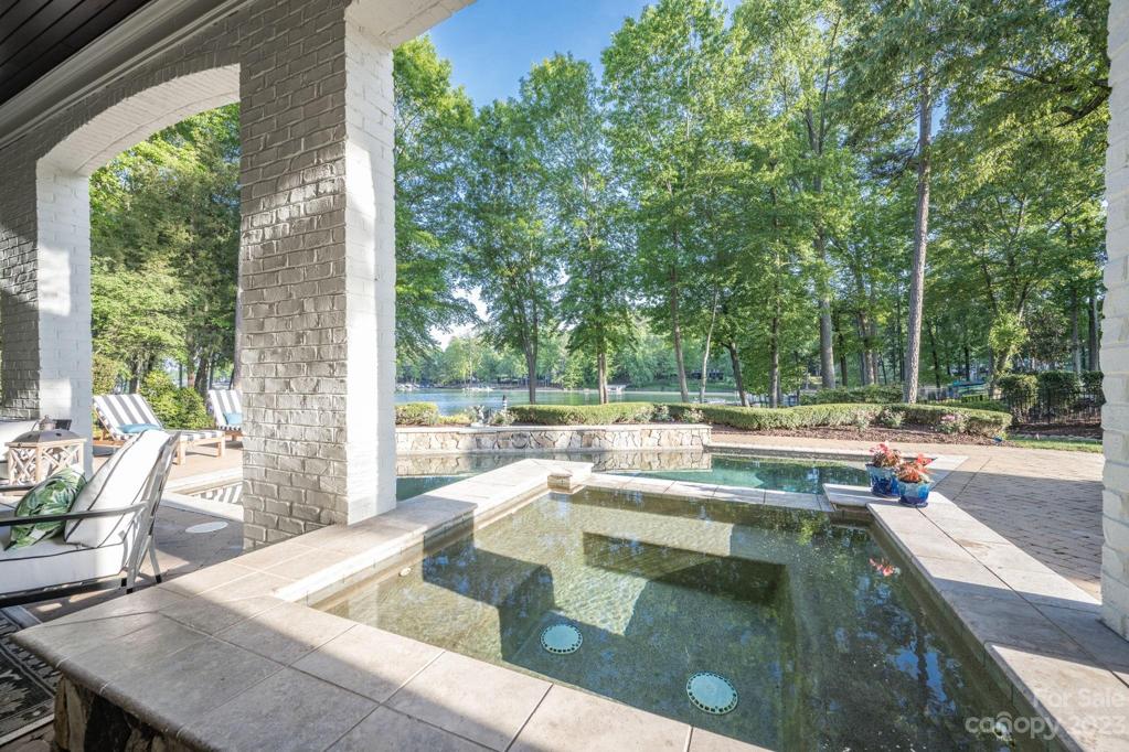 Waterfront Half Covered Hot Tub with Waterfall Overflowing into Inground Pool