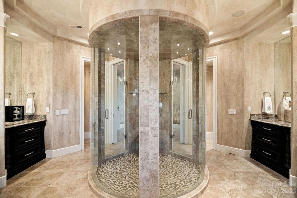 Double vanities with crystal fixtures and enclosed glass circular shower, don't miss the his and hers water closets