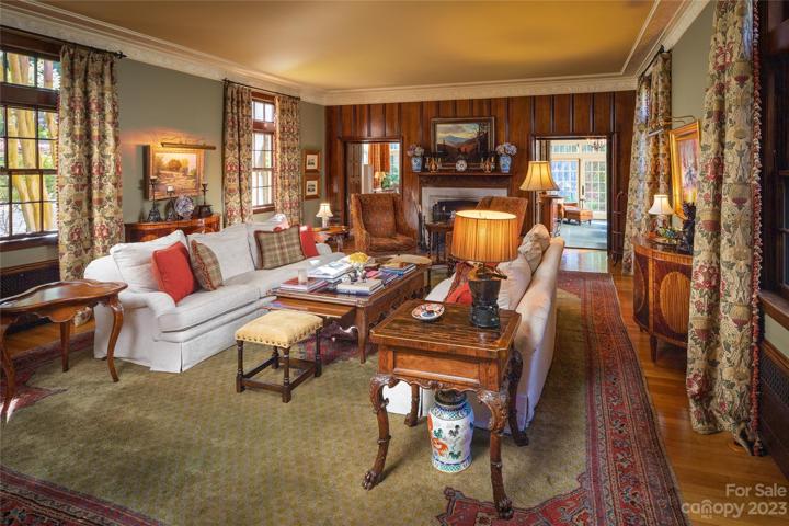 The living room boasts intricate crown molding, a cozy fireplace (one of many) and gleaming hardwood floors