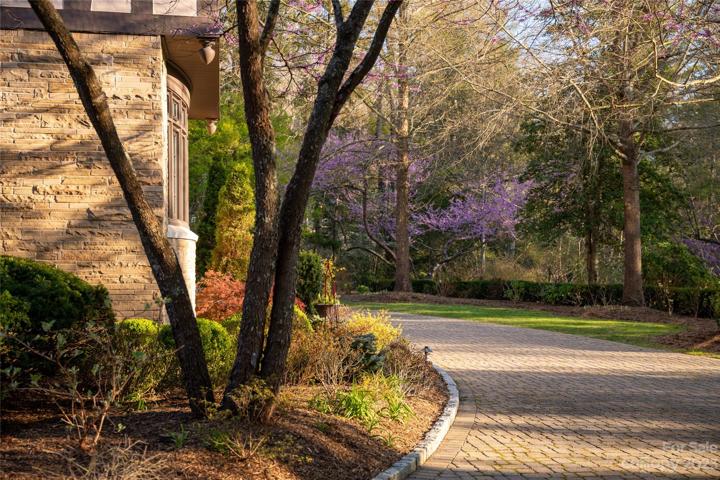 A cobblestone winding approach road in the midst of the lush landscaping sets the stage