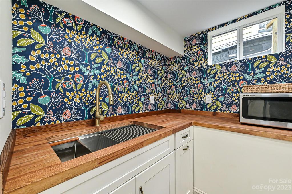 Single bowl stainless sink, champagne gold fixtures and BOLD wallpaper