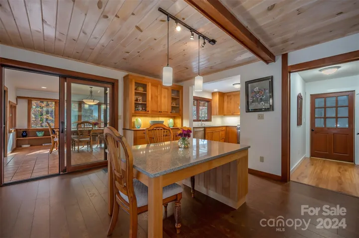 Dining island looking toward kitchen and sunroom/dining room. Open door to the right leads to the mudroom/laundry room and the closed door leads to the garage.