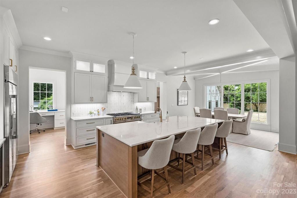 The well-appointed kitchen boasts an oversized island with quartz countertops, custom cabinetry. and premium appliances.