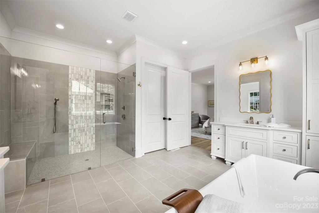 Primary ensuite bathroom features a floating bathtub and oversized, walk-in shower.