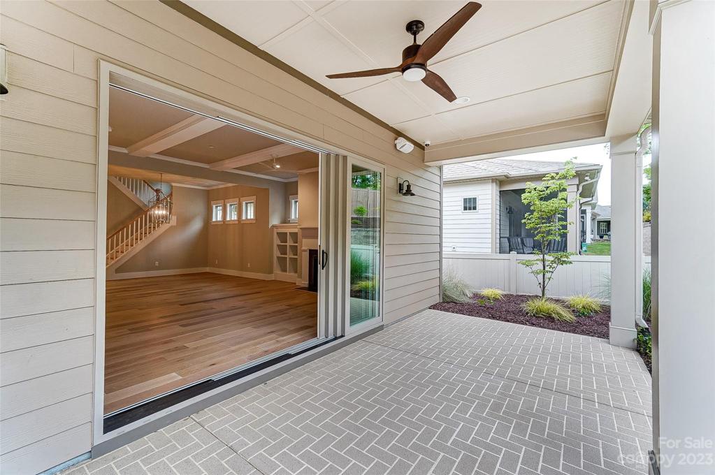 Covered rear porch with ceiling fan and multi-slide door.