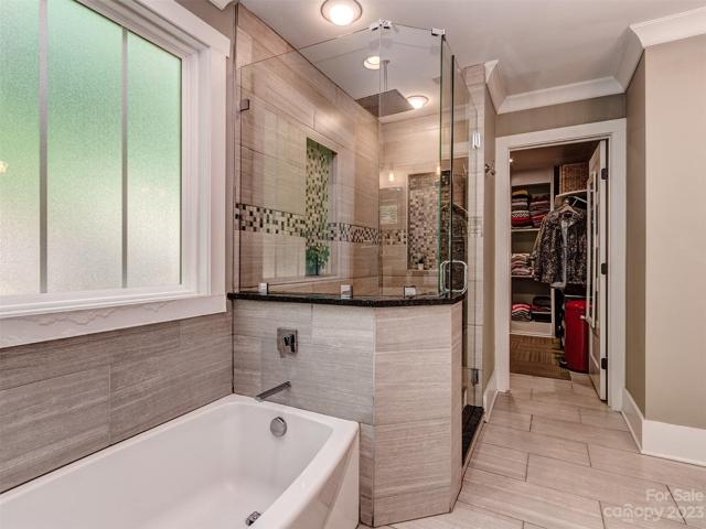 Barn Doors Open to your Primary Bath with Custom Dual Vanities, Tile Flooring, Custom Walk-In Shower, Soaking Tub and Lare Walk-in Closet.