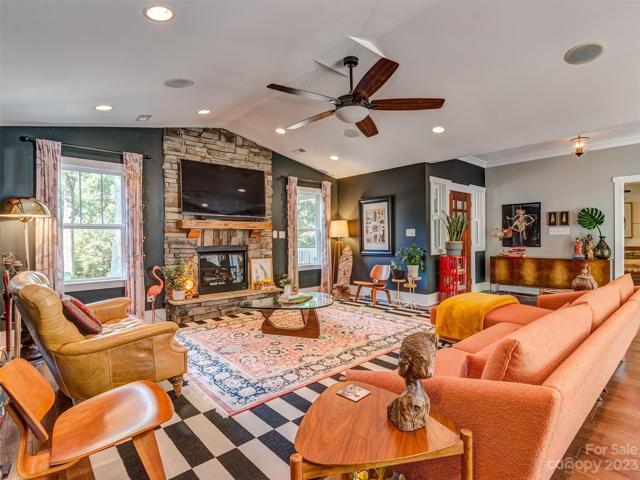 Great Room with vaulted ceiling, gas log fireplace, recessed lights, built-in speakers, & hardwood floors.