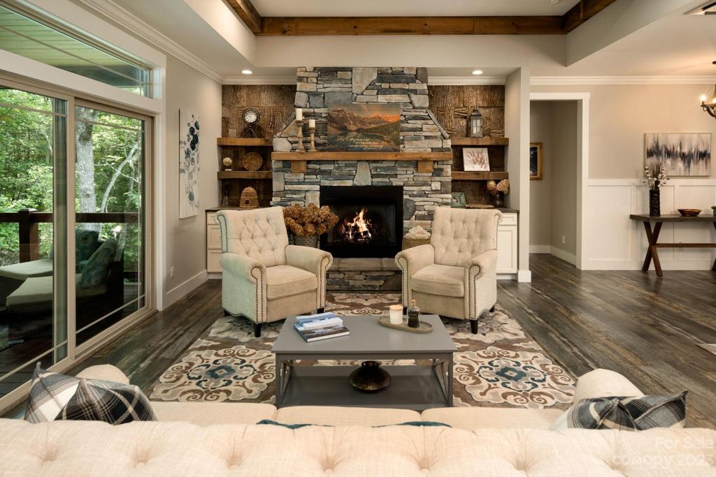 The great room boasts charming exposed beam accents, an impressive stone fireplace with mantle and custom birch built-ins, and a full wall of windows that allow for an abundance of natural light.