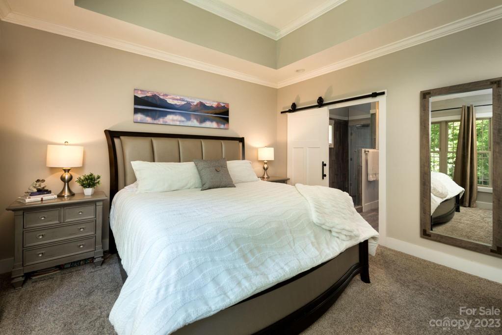 The gracious master suite is located on the main level has dramatic tray ceilings, charming barn door entry, crown molding and walk-in closet with closet system