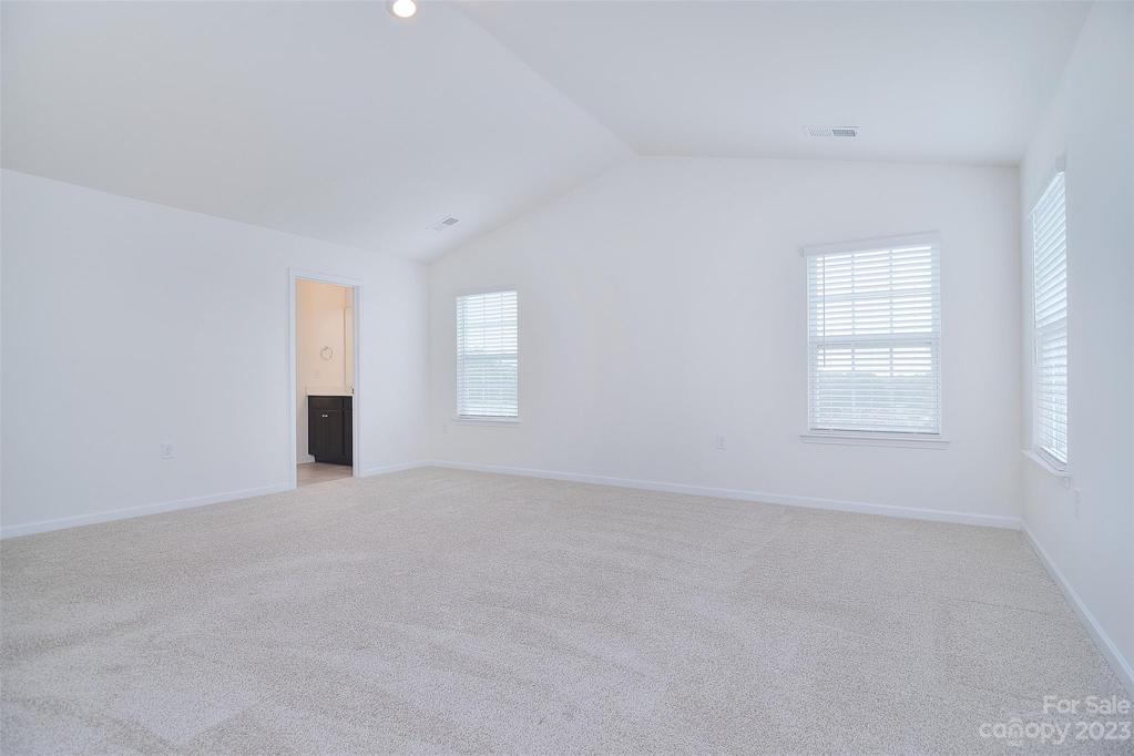 Windows offer natural light from all angles and the vaulted ceilings only enhance the spaciousness of this primary bedroom