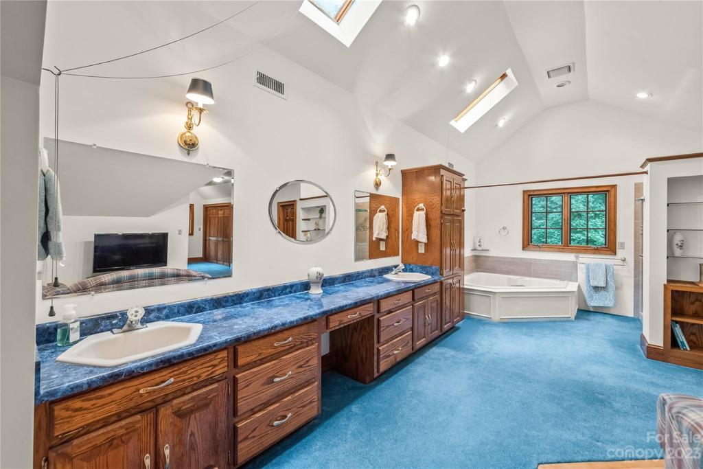 Double vanity in Primary suite with skylights overhead and recess lighting