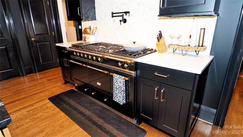 LaCanche® Dual Fuel 54" French Range with: 6 burners, double oven and warming cup board. Marble back splash and white quartz countertops.