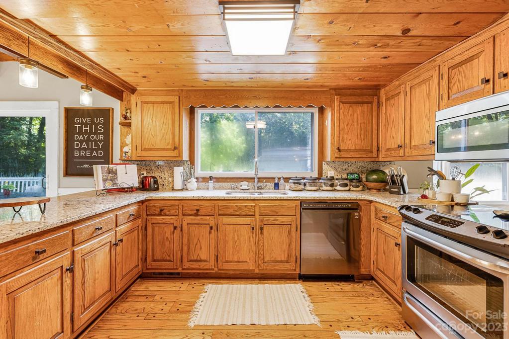 Wood floors and wooden ceilings in this dreamy Kitchen! Window view of the deck, backyard and the Barn.