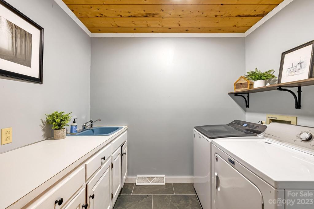Laundry room with tile floors and plenty of room for folding clothes and storage. Notice that vintage blue sink!