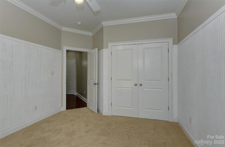 Bedroom 3 on main level, partial bead board on walls, ceiling fan w/light, crown molding and carpet.