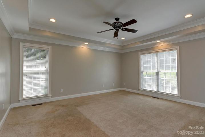 Primary bedroom on main level with trey ceiling, crown molding, ceiling fan, recessed lighting, 2 inch blinds on windows.