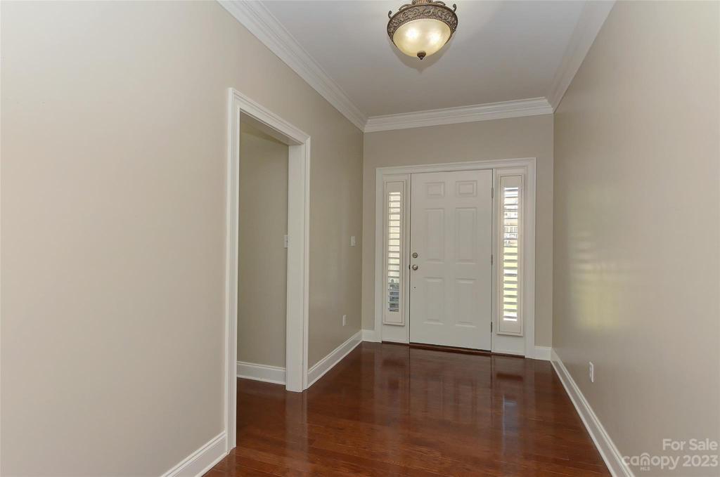 Foyer w/hardwood floors. plantation shutter at door and thick crown molding.