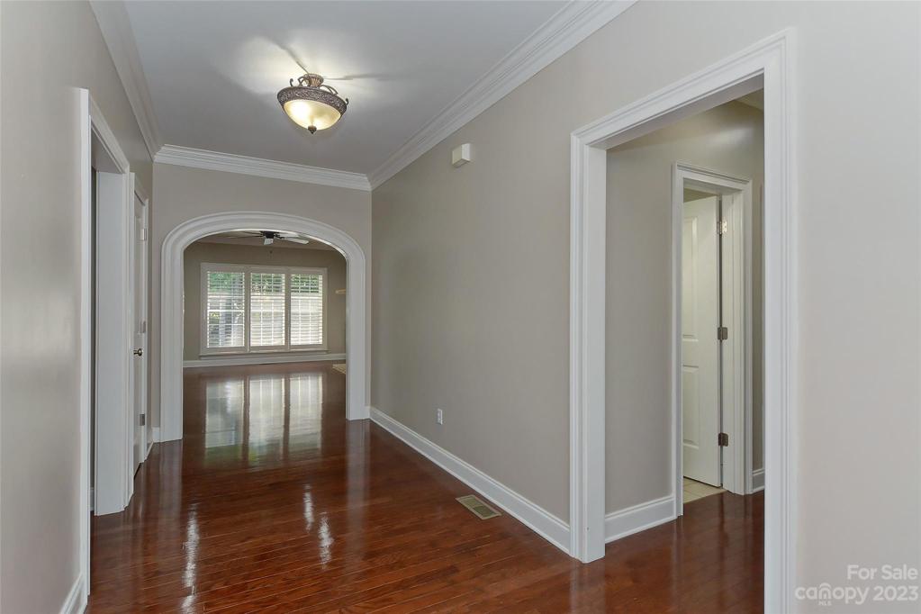 Foyer looking in showing off gleaming hardwood floors, arch way and crown molding.