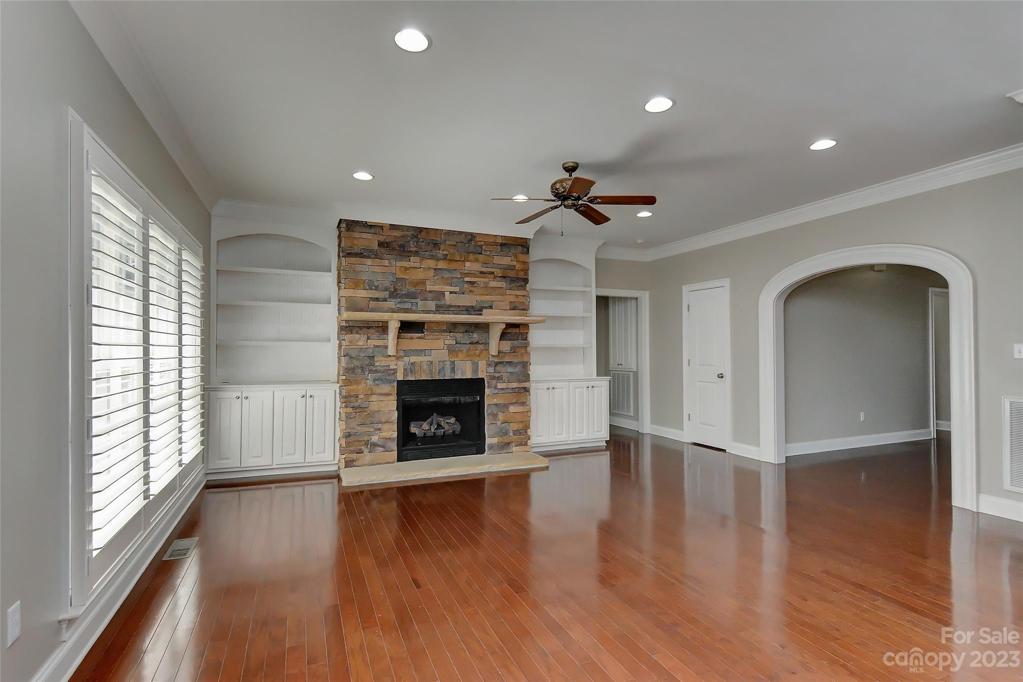 Family room w/stacked stone fireplace w/gas logs, mantel, builtins on both sides, ceiling fan, recessed lighting, plantation shutters on windows and gleaming hardwood floors.