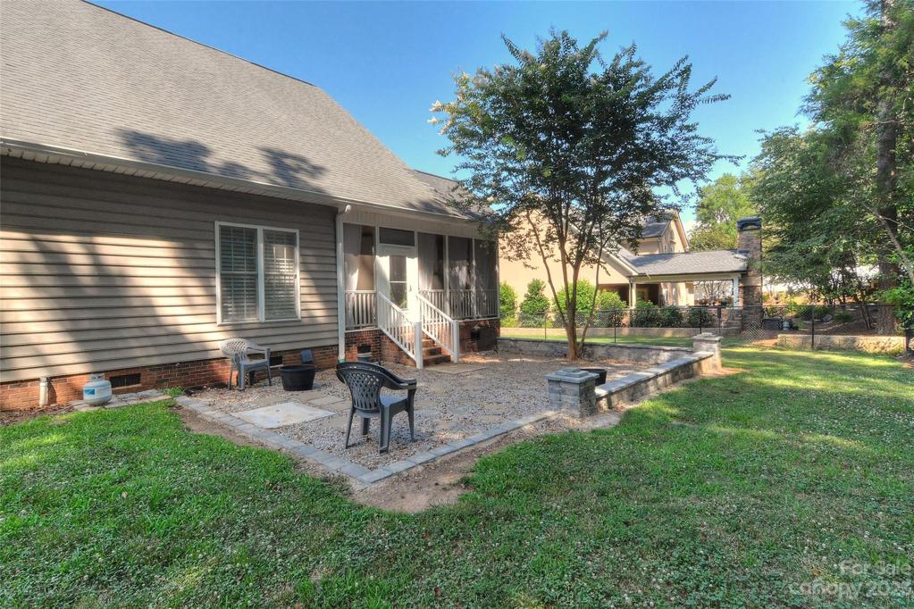 Gravel patio with partial stone wall surrounding it.