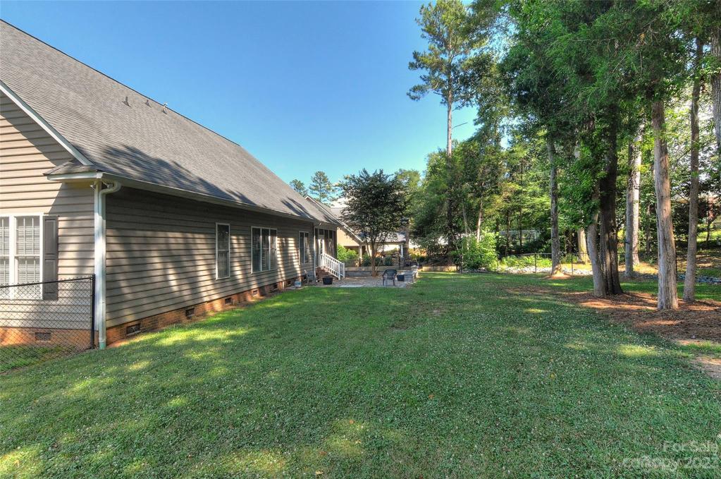 The side to back yard. back yard is fenched in and features solar motion lighting in 2 trees.