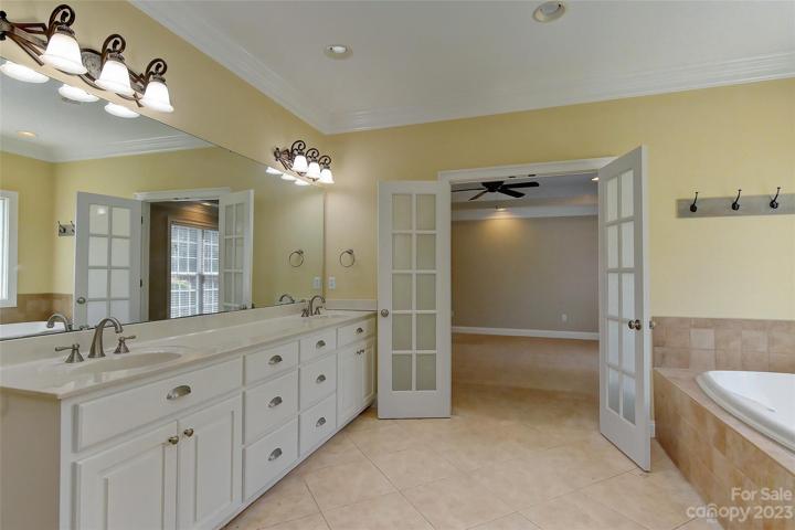 Big primary bath w/dual vanities and offering tons of space, tile flooring and french doors
