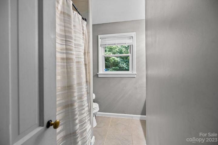 Full second bathroom view from hallway. Tub and shower with light colored tile floor.