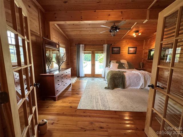 French door entrance to primary bedroom. . . wood floors and wood beams, exterior French doors out to the covered patio and pool.