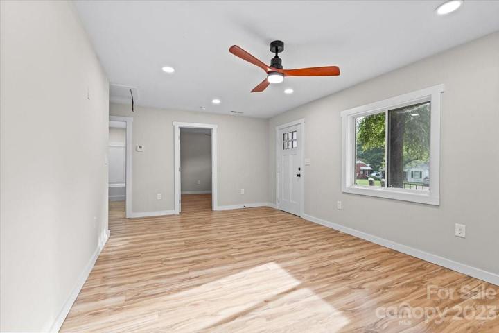 Spacious living room with modern ceiling fan and natural light!