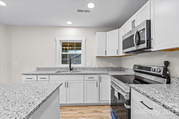 Fall in LOVE with your new kitchen featuring a brand new stove and microwave, white cabinets with black fixtures and granite countertops!