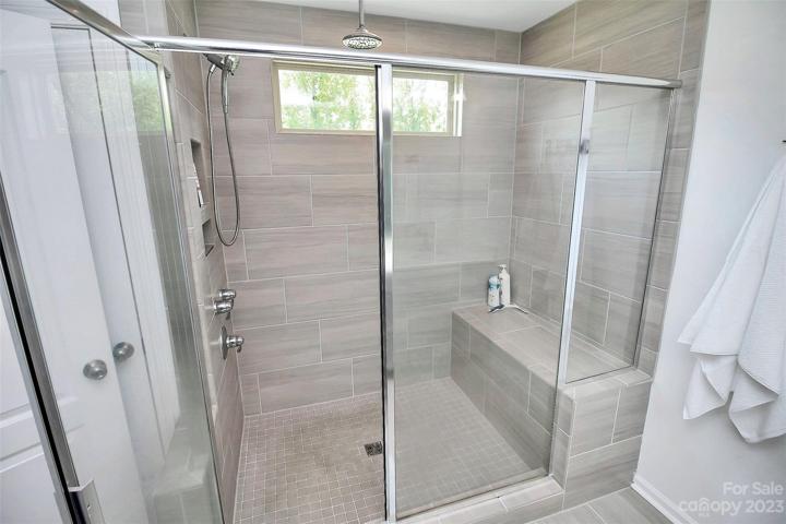 Floor to ceiling tiled shower, bench seat and transom window into private backyard.